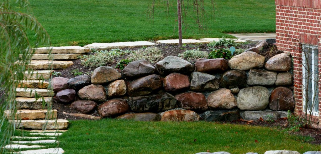 Retaining wall in landscape featuring Glacial Granite boulders from Green Stone | Noblesville and Indianapolis, Indiana